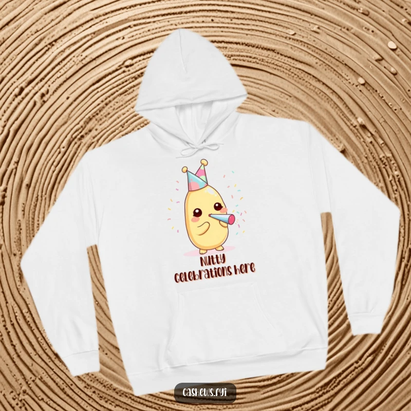 Funny kawaii cashew wearing a party hat, blowing a confetti popper on a cozy hoodie.
